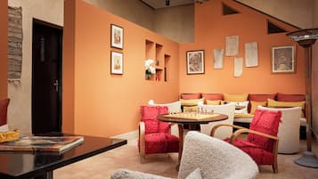 Una habitación con sofá, sillas, una mesa y obras de arte en las paredes.