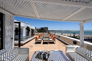 A terrace with outdoor seating, a view of the beach, and a white pergola structure. - Madada Mogador (Essaouira)