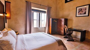 Une chambre d’hôtel avec un lit, une commode, un bureau et une fenêtre avec des rideaux.