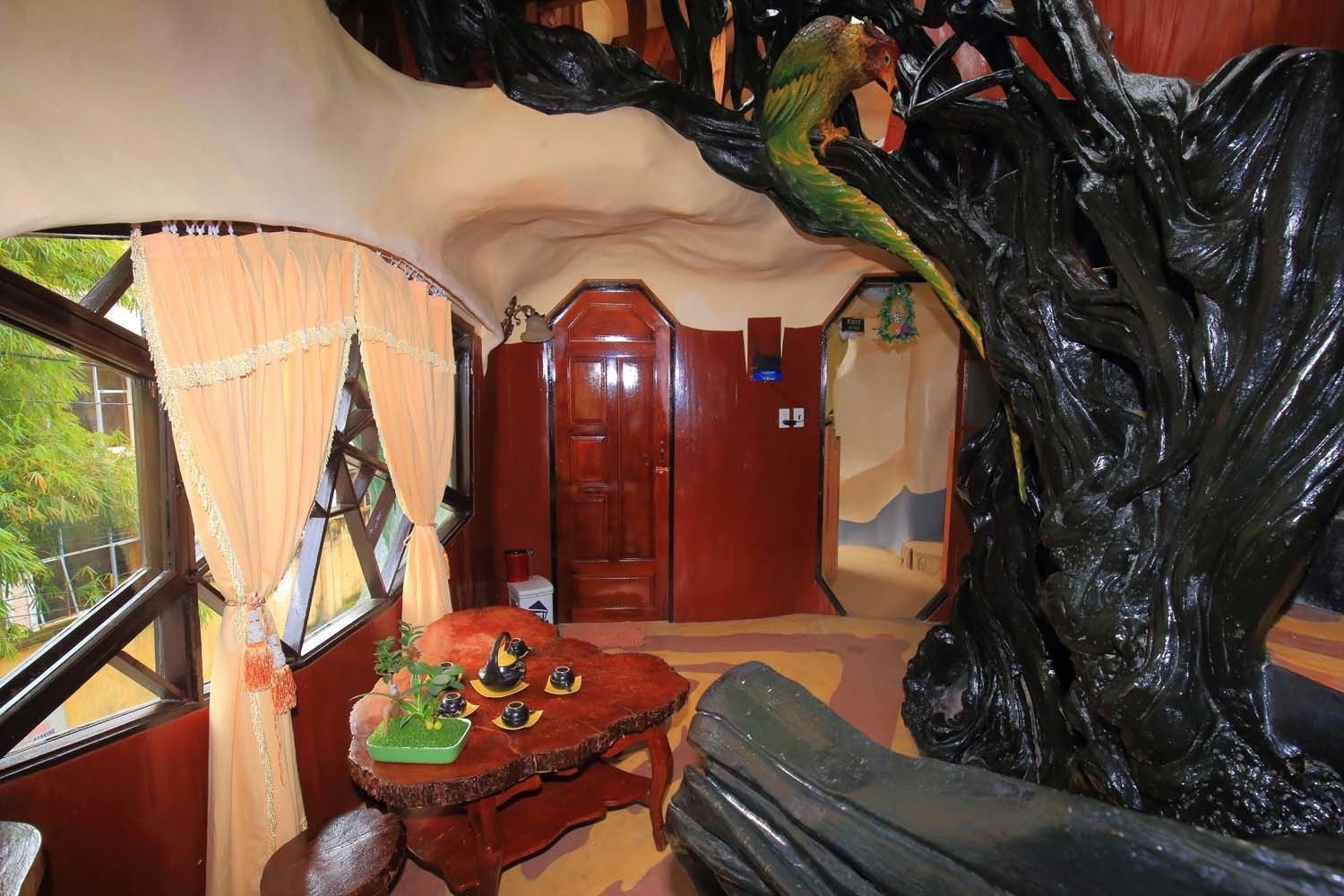 A room with a large tree sculpture, a wooden door, and a small table with decorative items.