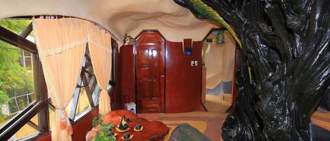Ein Zimmer mit einer großen Baumskulptur, einer Holztür und einem kleinen Tisch mit dekorativen Gegenständen.