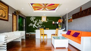 En moderne hotellobby med en receptionsdisk, hvide sofaer og et farverigt loft.