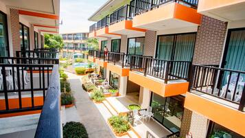 A modern building with multiple balconies, outdoor seating areas, and a pool.