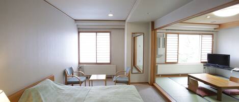 A hotel room with a bed, a desk, a chair, a television, and a large mirror.