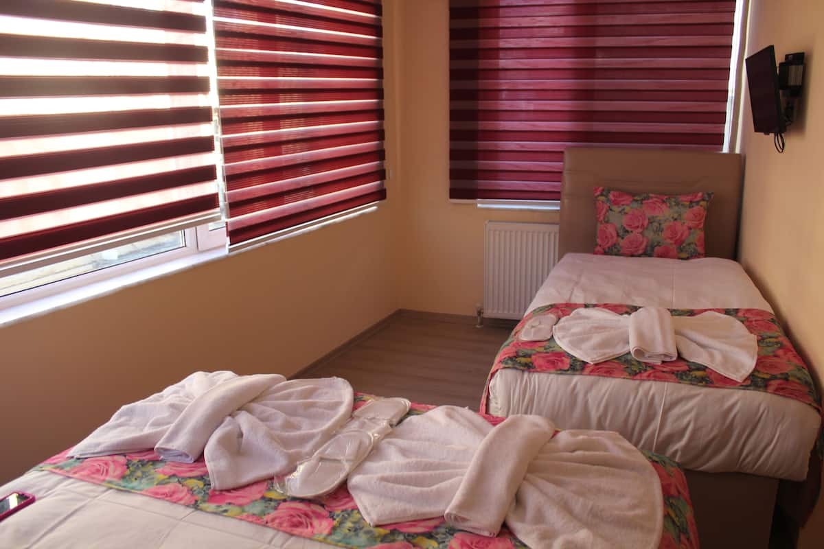 A hotel room with two beds, each with floral bedding and towels.