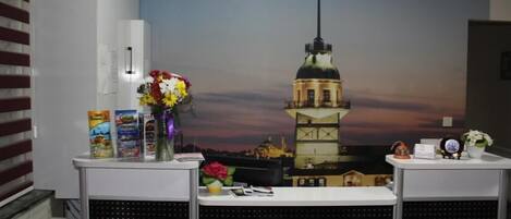 A reception desk with a cityscape mural, a vase of flowers, and informational brochures.