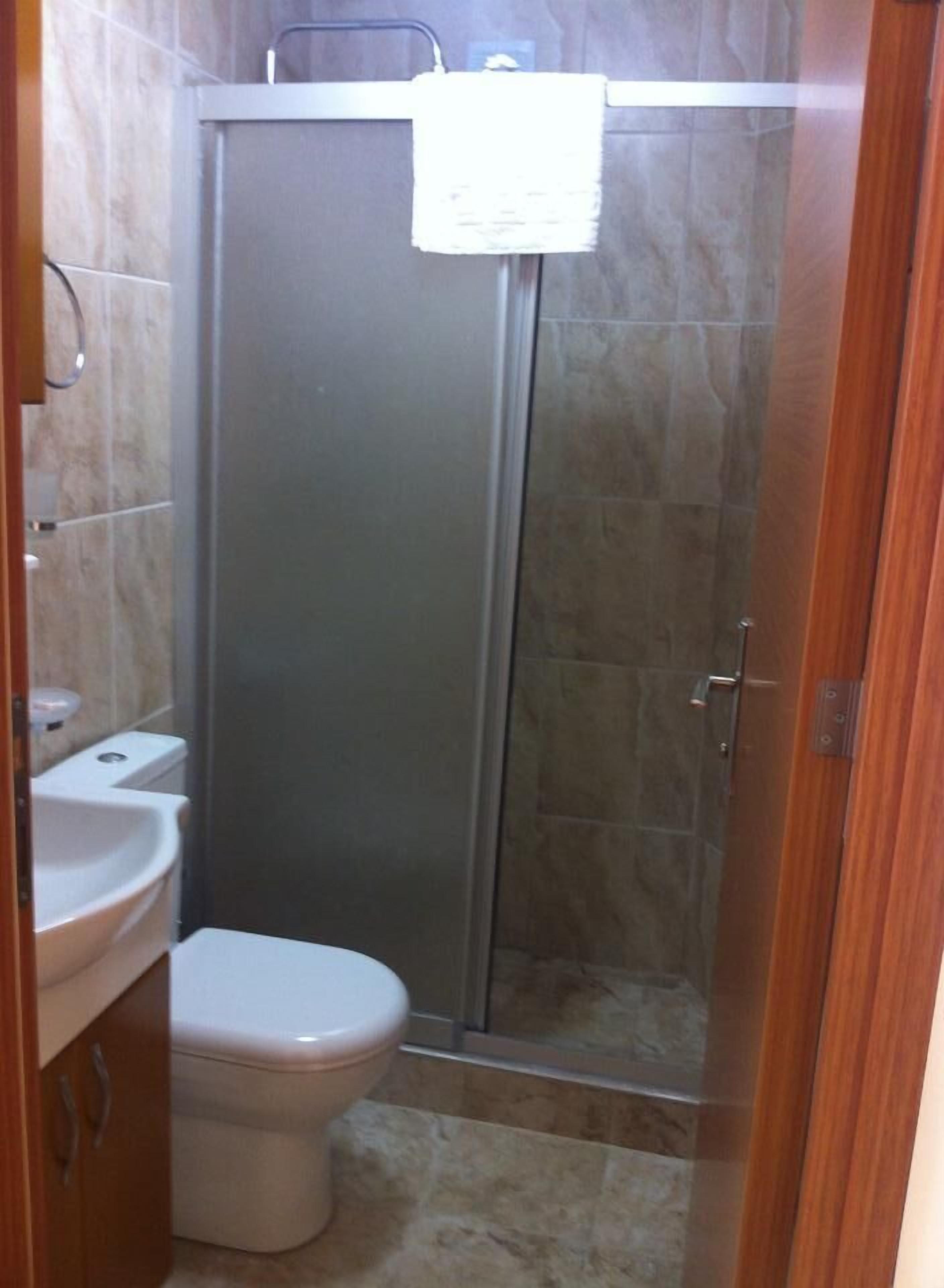 A bathroom with a toilet, sink, and a glass-enclosed shower stall.