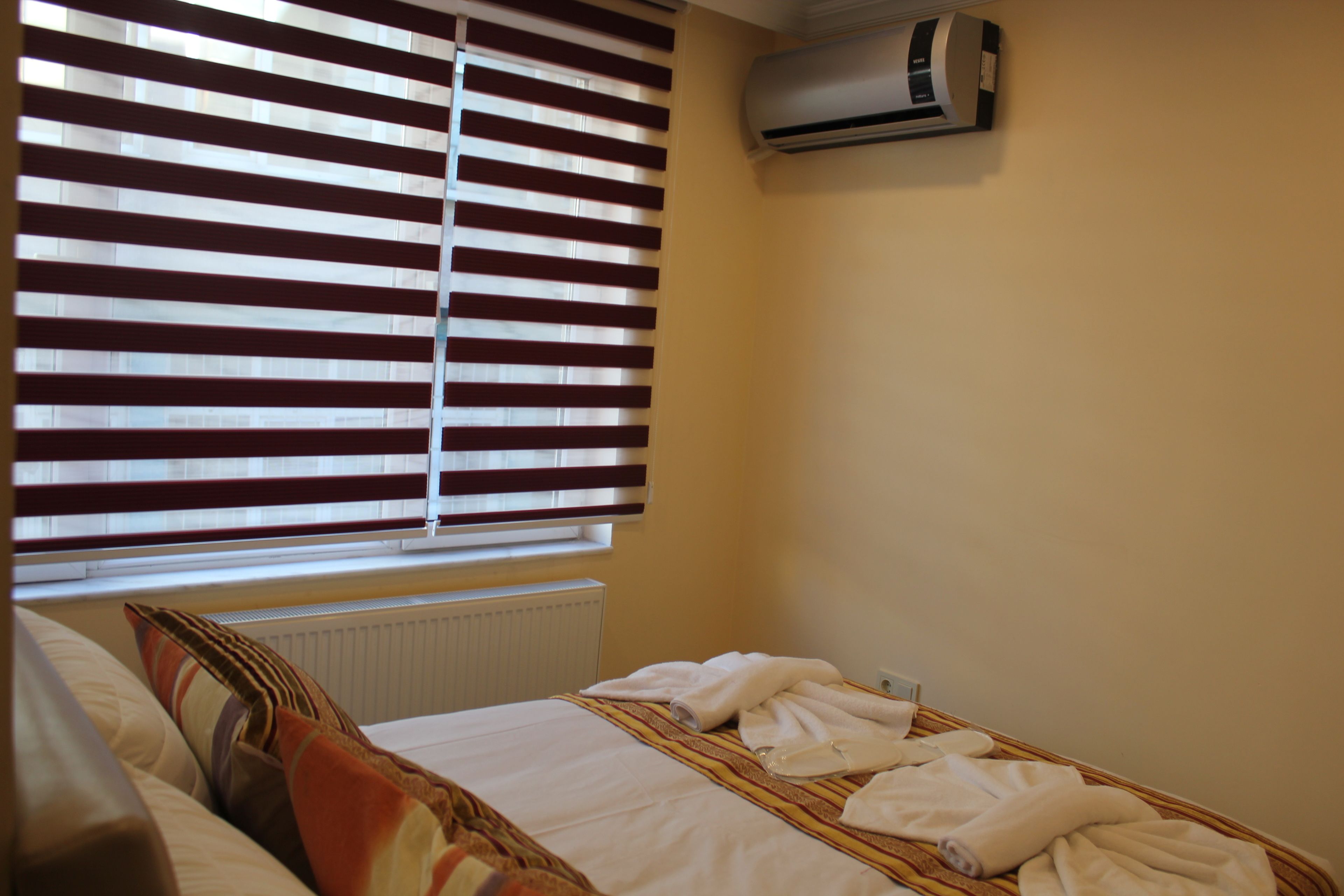 Una habitación de hotel con cama, un radiador y una ventana con persianas.
