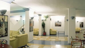 Een ruime lobby met een zwart-wit schaakbordvloer, meerdere zithoeken en kunstwerken aan de wanden.