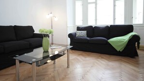 A modern living room with two black sofas, a glass coffee table, and a floor lamp. - Prague Central Exclusive Apartments (Prague)