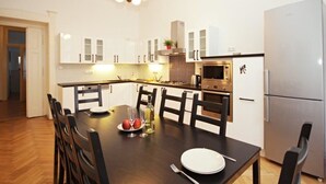 A modern kitchen with white cabinets, a dining table with chairs, a refrigerator, and a microwave. - Prague Central Exclusive Apartments (Prague)