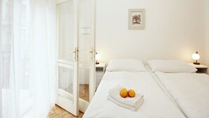 A hotel room with a bed, two bedside lamps, a framed picture on the wall, and a door with a glass panel. - Prague Central Exclusive Apartments (Prague)