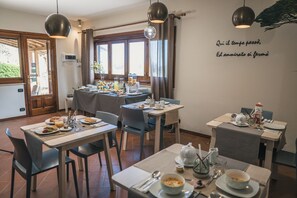 Ein Essbereich mit Tischen, die für ein Frühstück gedeckt sind, einschließlich Teller, Tassen und Besteck.