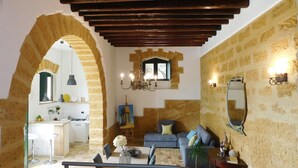 Una sala de estar con un sofá, una mesa de comedor y una cocina visible a través de un arco.