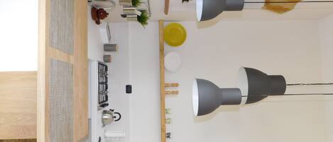 Cocina moderna con estufa a gas, lavamanos y dos lámparas colgantes.