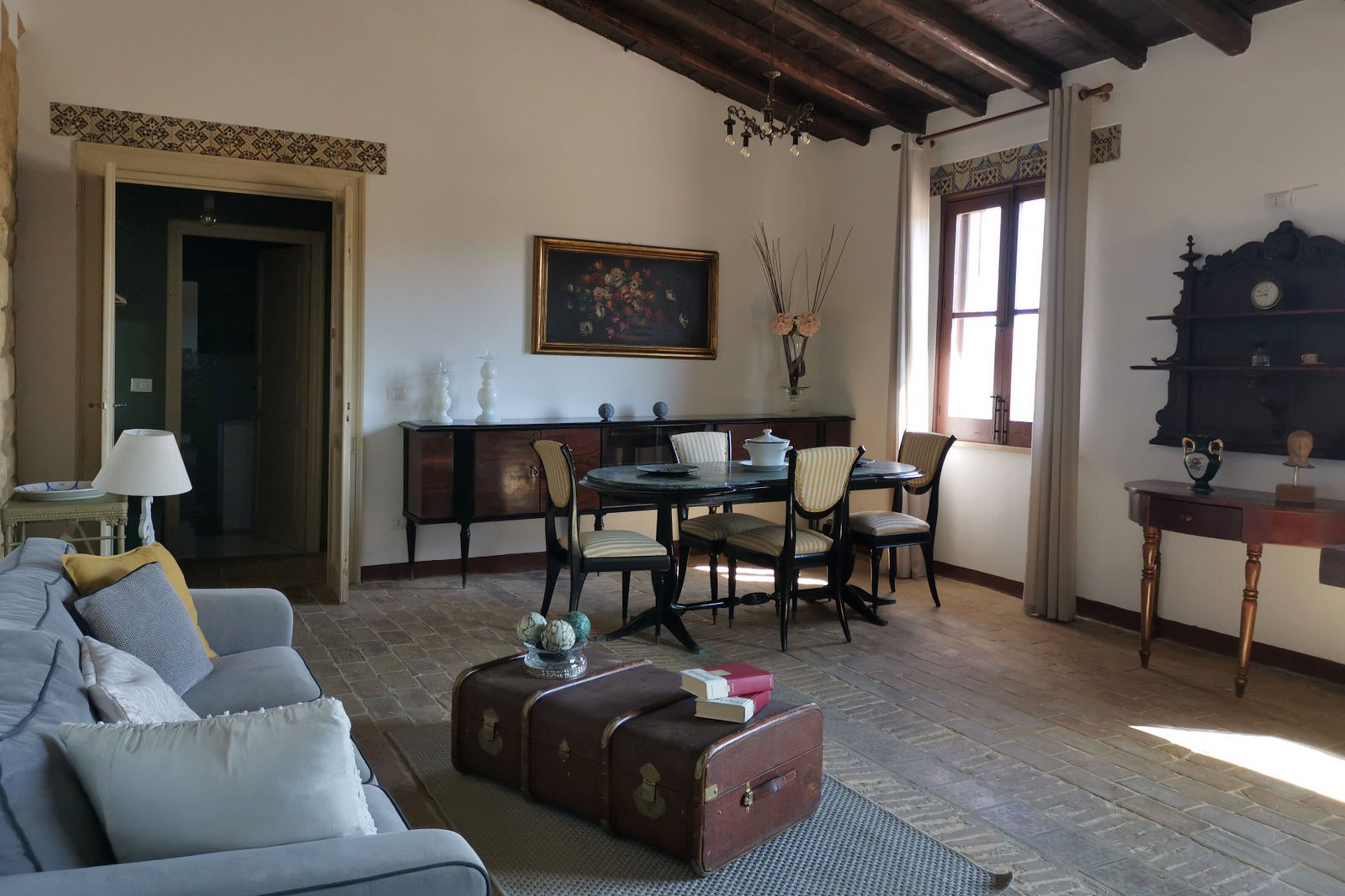 A living room with a sofa, a table with chairs, a fireplace, and a bookshelf.