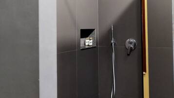 A modern shower area with a glass door, a handheld showerhead, and a towel rack.