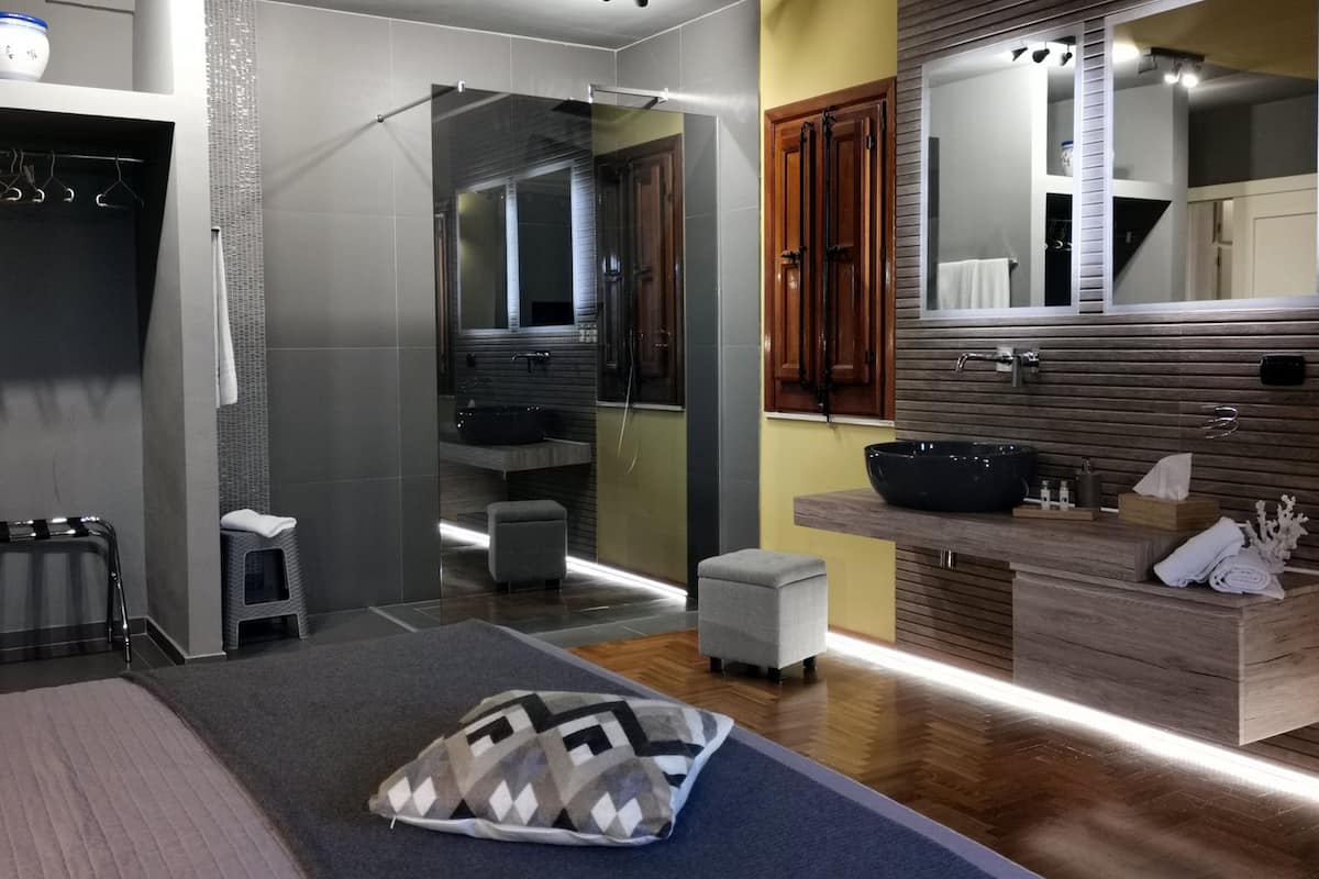 Een moderne badkamer met een douchecabine van glas, een houten wastafelmeubel met een zwarte wasbak en een grote spiegel.