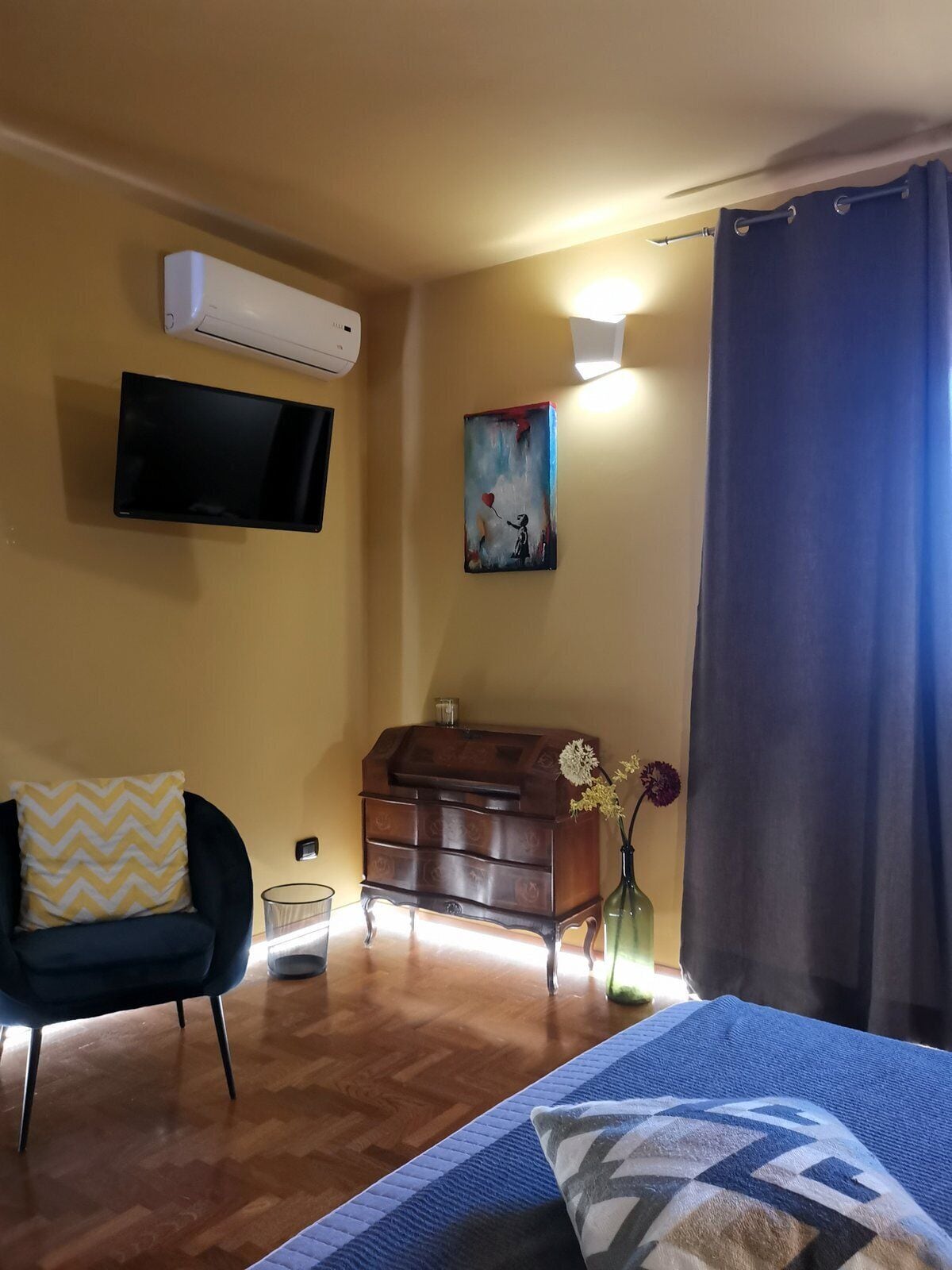 Ein Zimmer mit einem Bett, einem Sessel, einem Schminktisch und einer Klimaanlage.