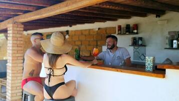 A bar area with a wooden ceiling, brick walls, and a counter with various bottles and a decorative box.