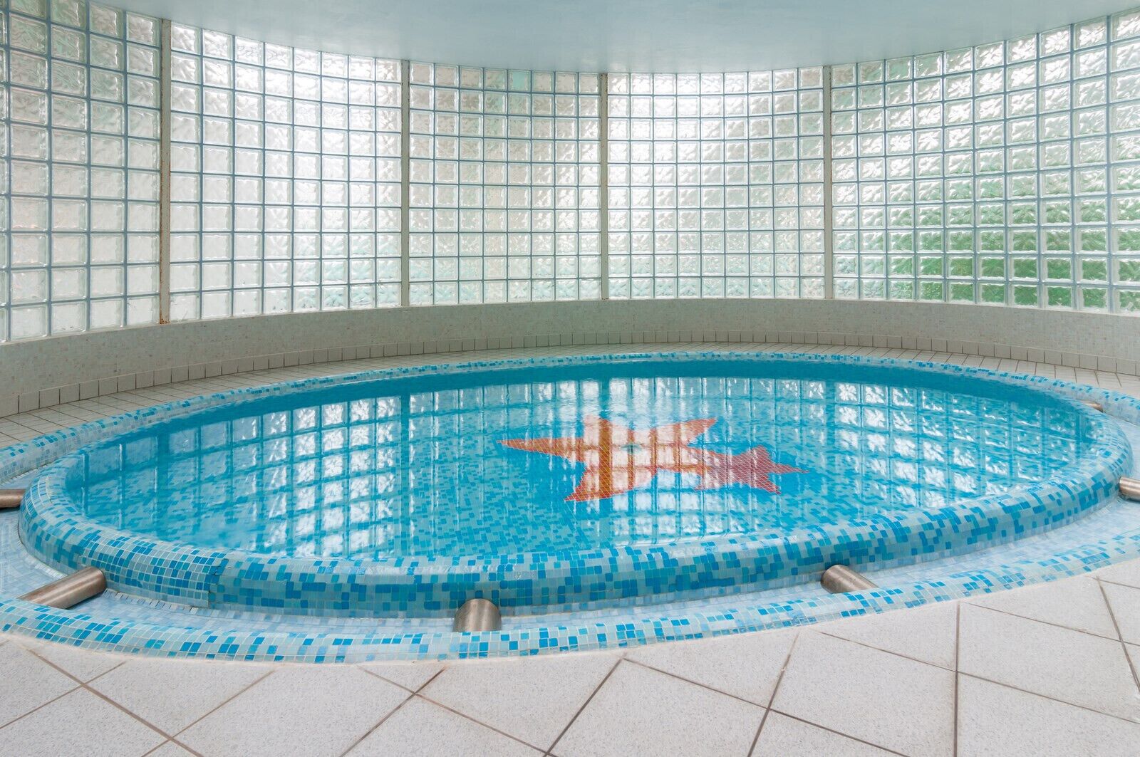 Ein Innenpool mit gefliestem Rand und blauem, klarem Wasser.