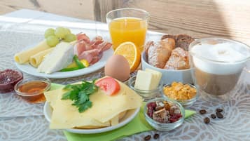 Una mesa de desayuno con diversos alimentos como queso, huevos, pan y café.