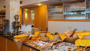 A buffet with various baked goods, including croissants and pastries, and a coffee machine. - Hotel Panoramik (Rio di Pusteria)