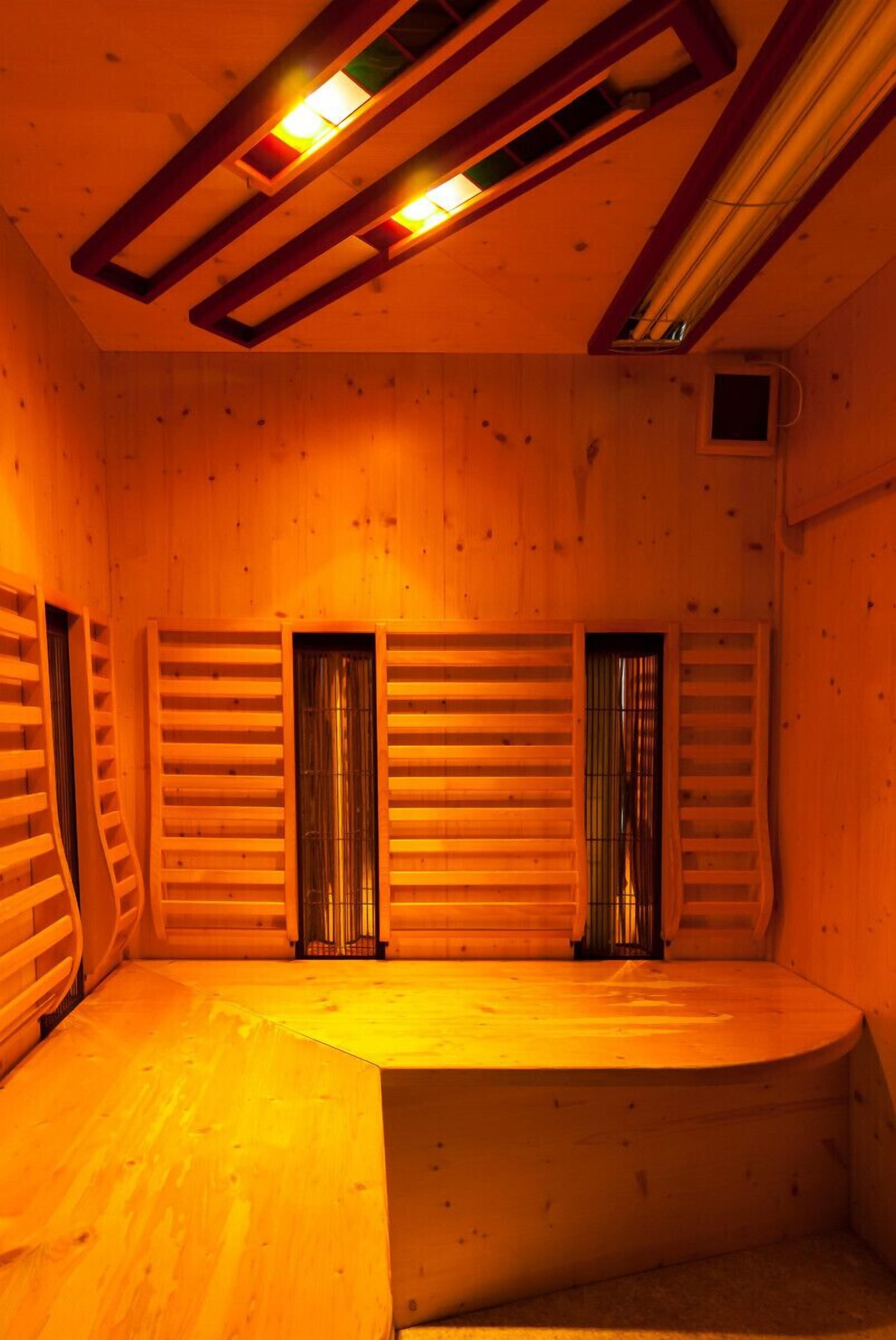 A wooden sauna room with benches and a sloped ceiling.