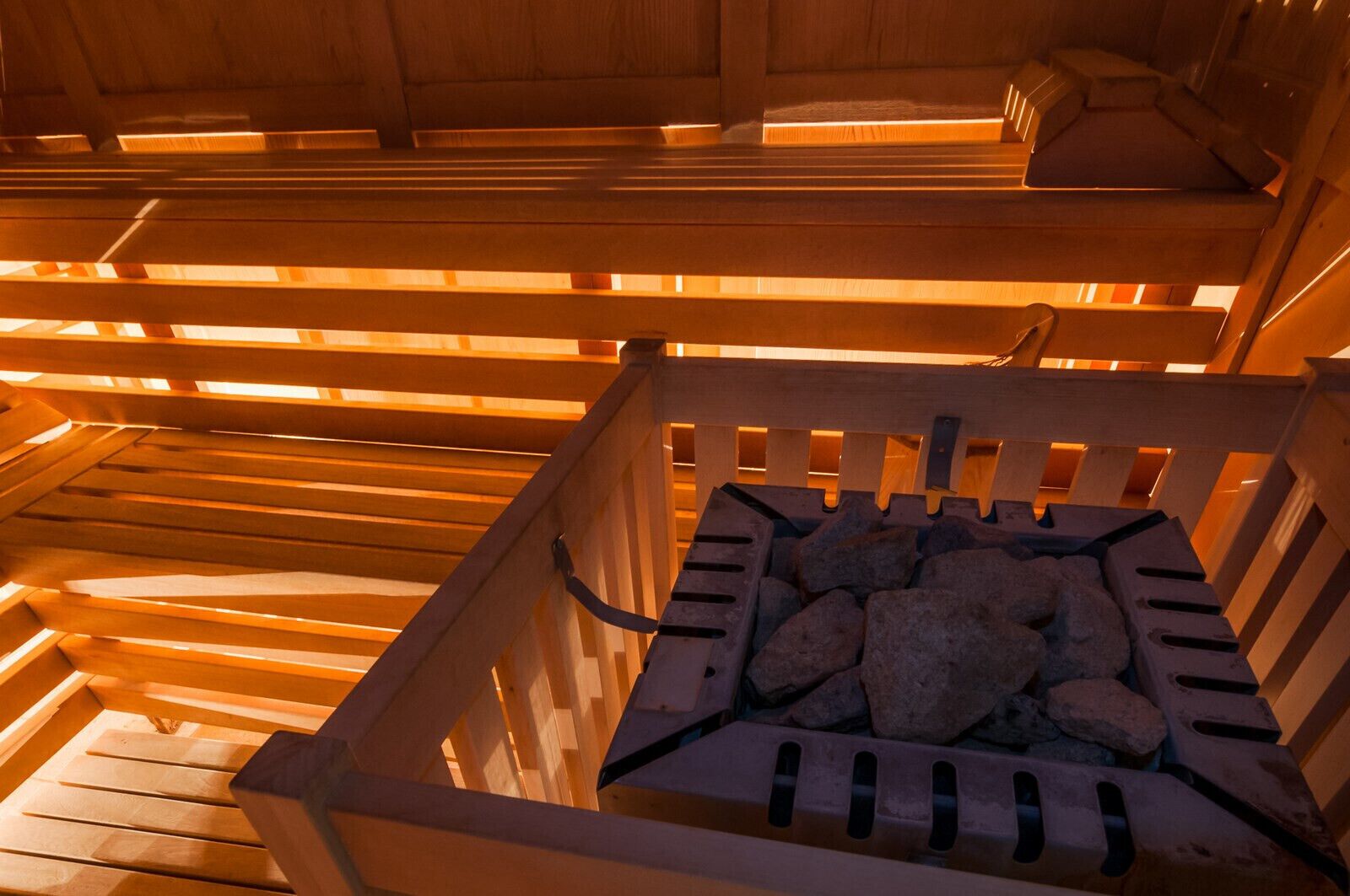 A sauna with wooden benches and a stone-filled container in the center.
