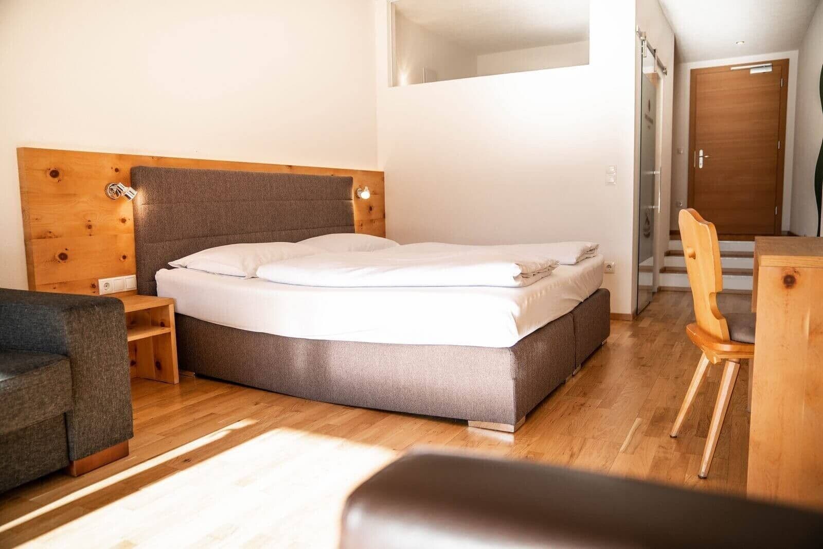 Un dormitorio moderno con cabecera de madera, cama, escritorio de madera y una silla.