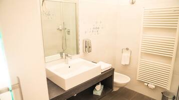 A modern bathroom with a white sink, mirror, and toilet.