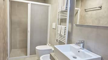 Une salle de bain moderne avec une douche, des toilettes et un lavabo surmonté d’un miroir.