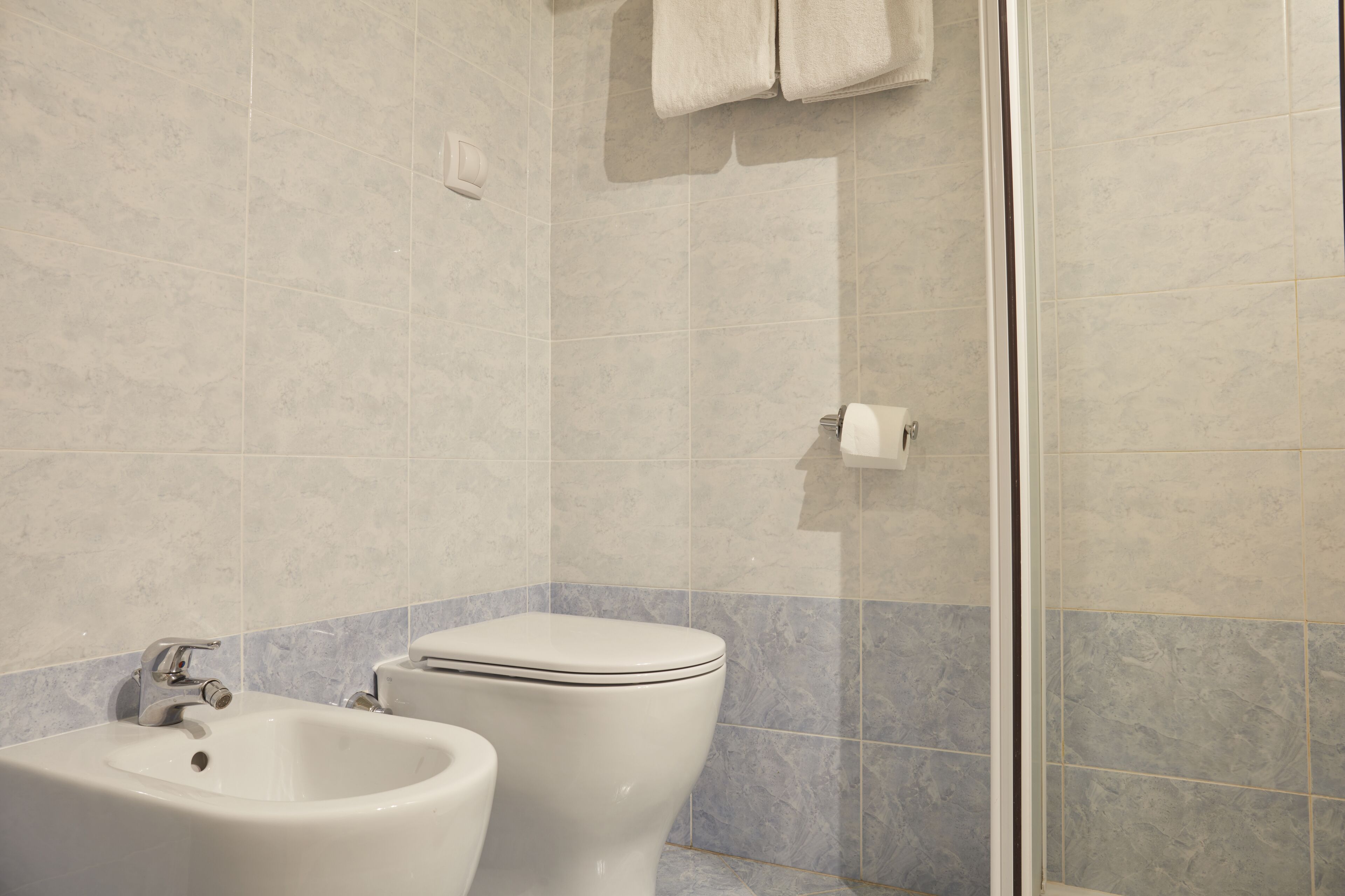 Un baño con bidé, inodoro y cabina de ducha de cristal.