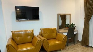 Una habitación con dos sillones de cuero, un televisor de pantalla plana montado en la pared, un escritorio con una silla y un espejo.