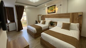 Habitación de hotel con dos camas, un escritorio, una silla, una mesita y un balcón con cortinas.