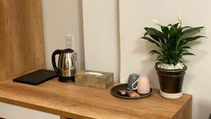 Un escritorio de madera con una tetera, una caja, una taza, un plato con aperitivos y una planta en maceta.