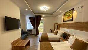 Habitación de hotel con dos camas, televisión, escritorio y un cuadro.