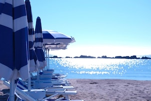 Perto da praia, espreguiçadeiras, guarda-sóis, toalhas de praia