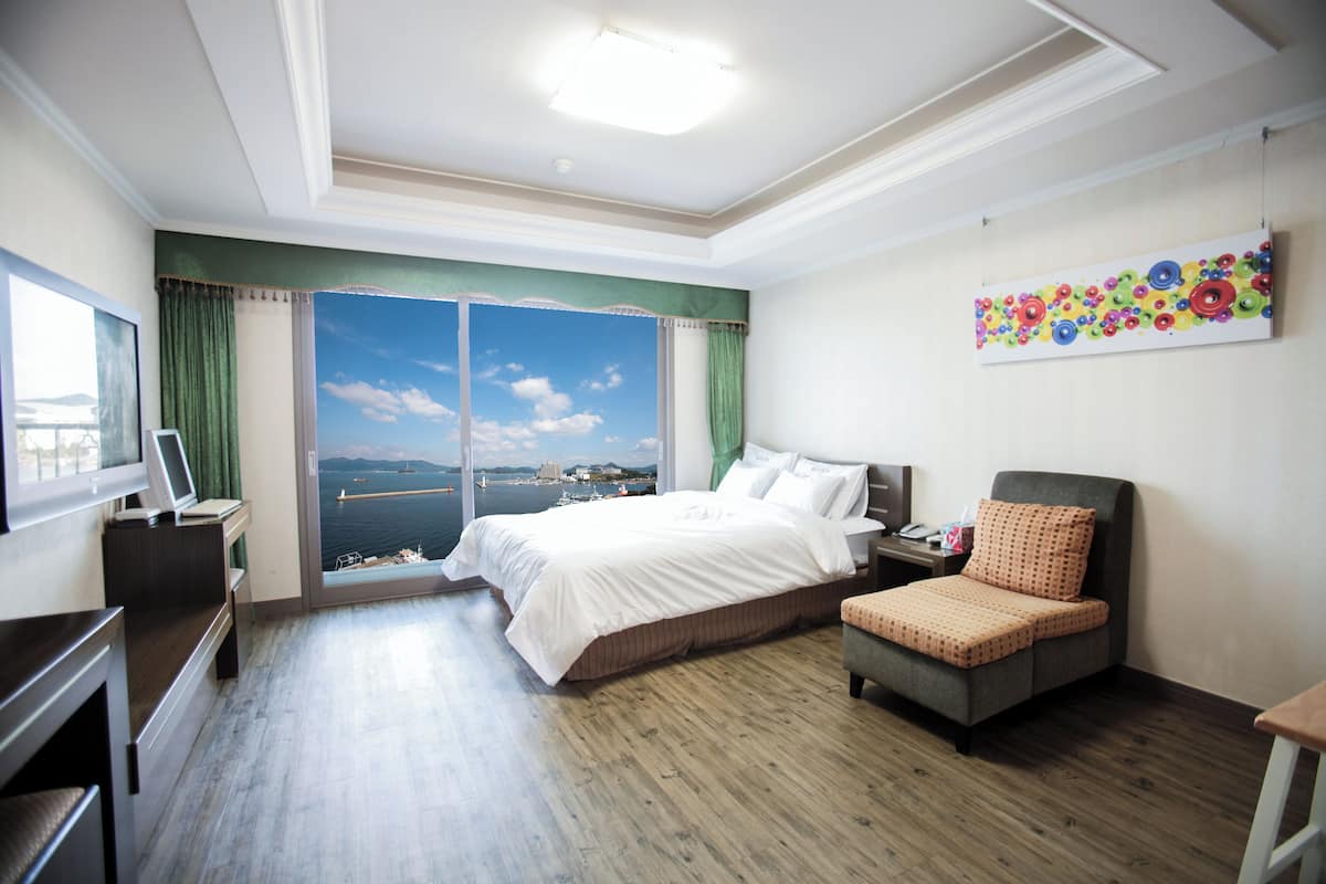 Habitación de hotel con una cama grande, un escritorio, una silla y vistas al mar.