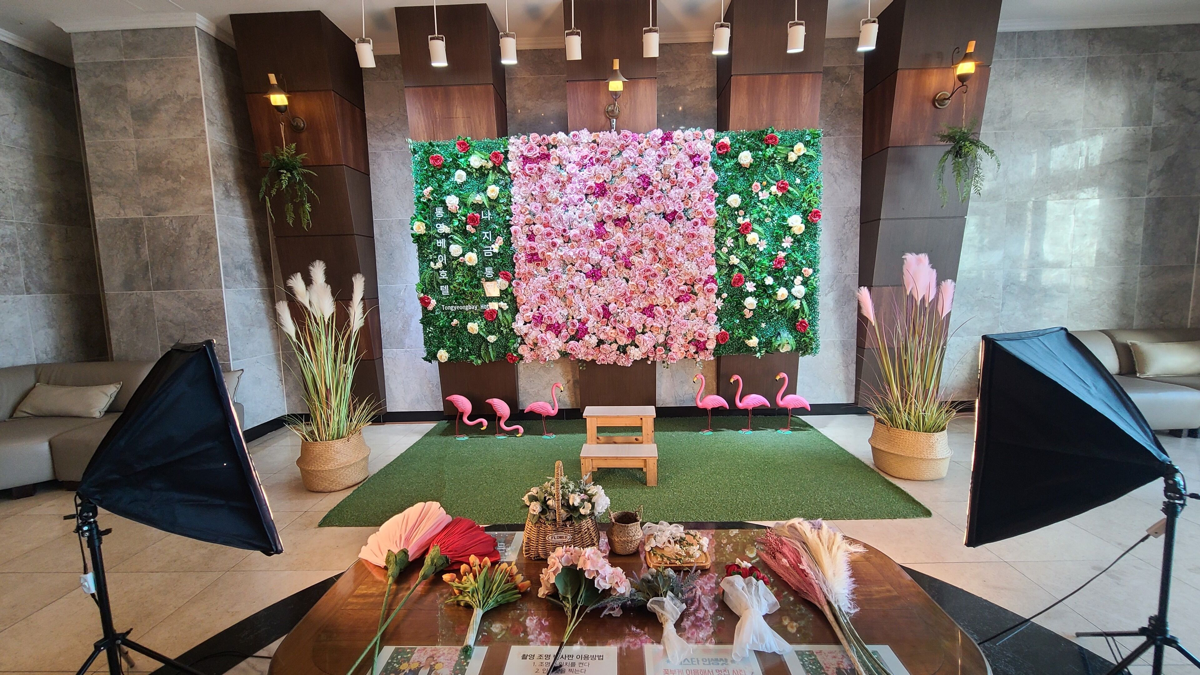 A room with a floral wall decoration, a wooden bench, and potted plants.
