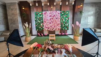 A room with a floral wall decoration, a wooden bench, and potted plants.