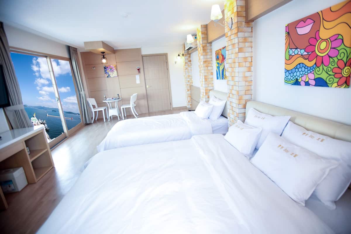 Habitación de hotel con una cama grande, un escritorio y vistas al mar.