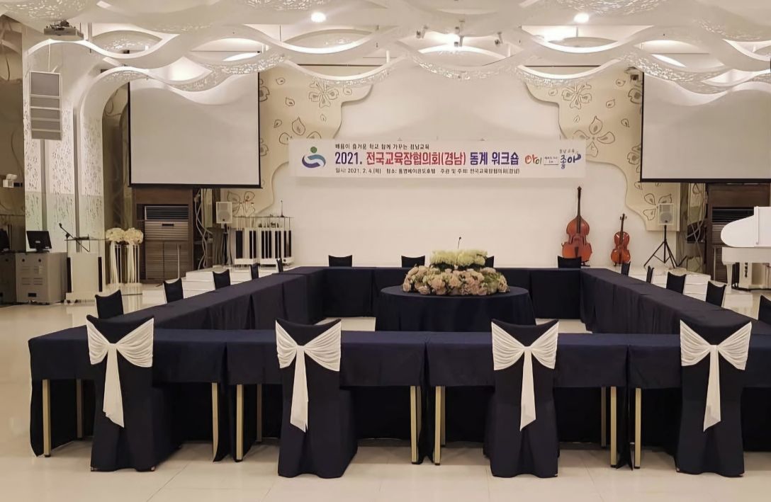 Un salón de conferencias con una larga mesa, sillas y una zona para presentaciones.