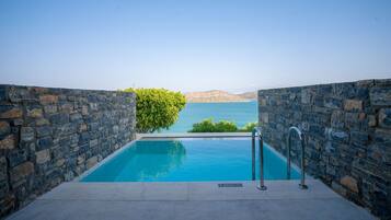 Una piscina infinita de paredes de piedra con vistas despejadas al mar y las colinas.
