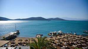 A beachside resort with sun loungers, umbrellas, and boats. - Royal Marmin Bay Boutique & Art Hotel - Adults Only (Agios Nikolaos)