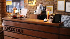 A wooden reception desk labeled "CHECK-OUT" with a small model train, a bowl of colorful candies, a "Tip Box," and a "Welcome" sign. - New Pera (Istanbul)
