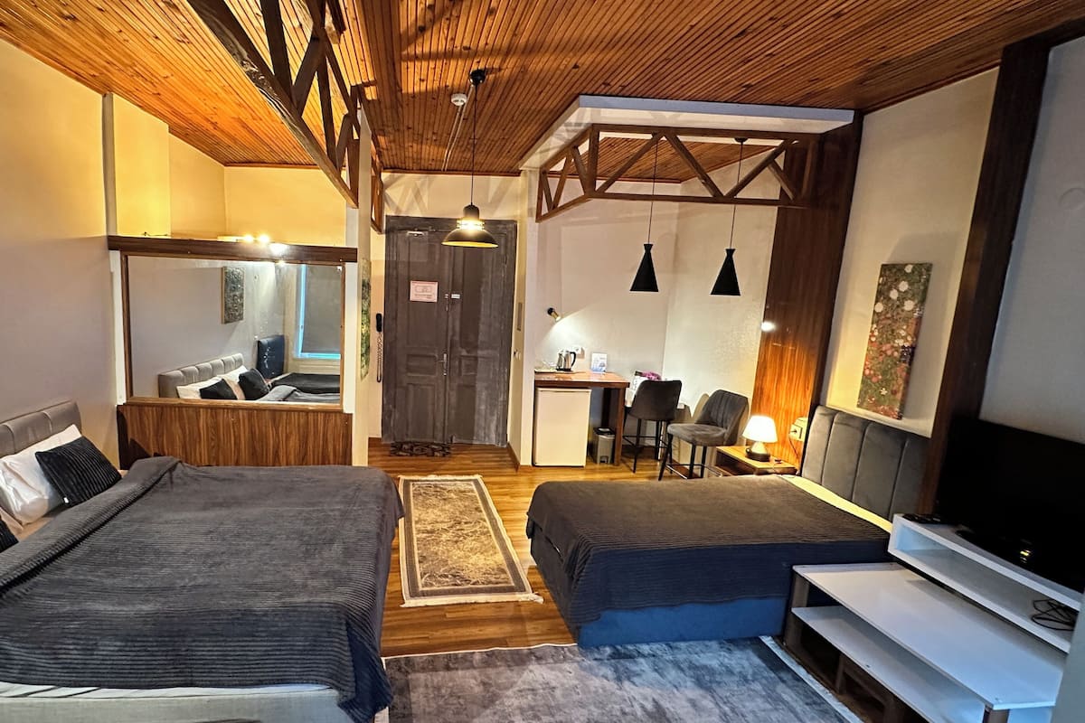 A modern bedroom with two beds, a desk, and a TV.