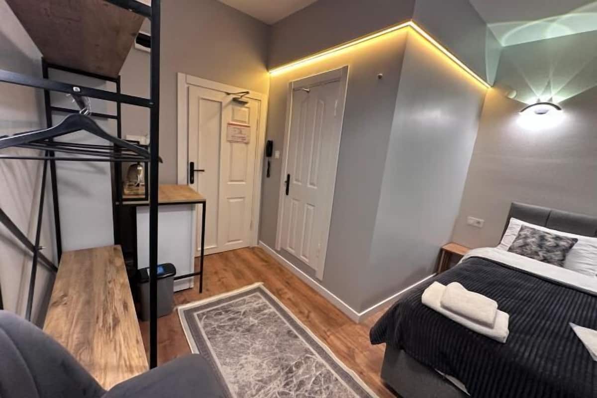A bedroom with a bed, bedside table, and a hanging clothing rack.