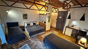 A room with two beds, a desk, a chair, a small kitchenette, and a door with a phone. - New Pera (Istanbul)