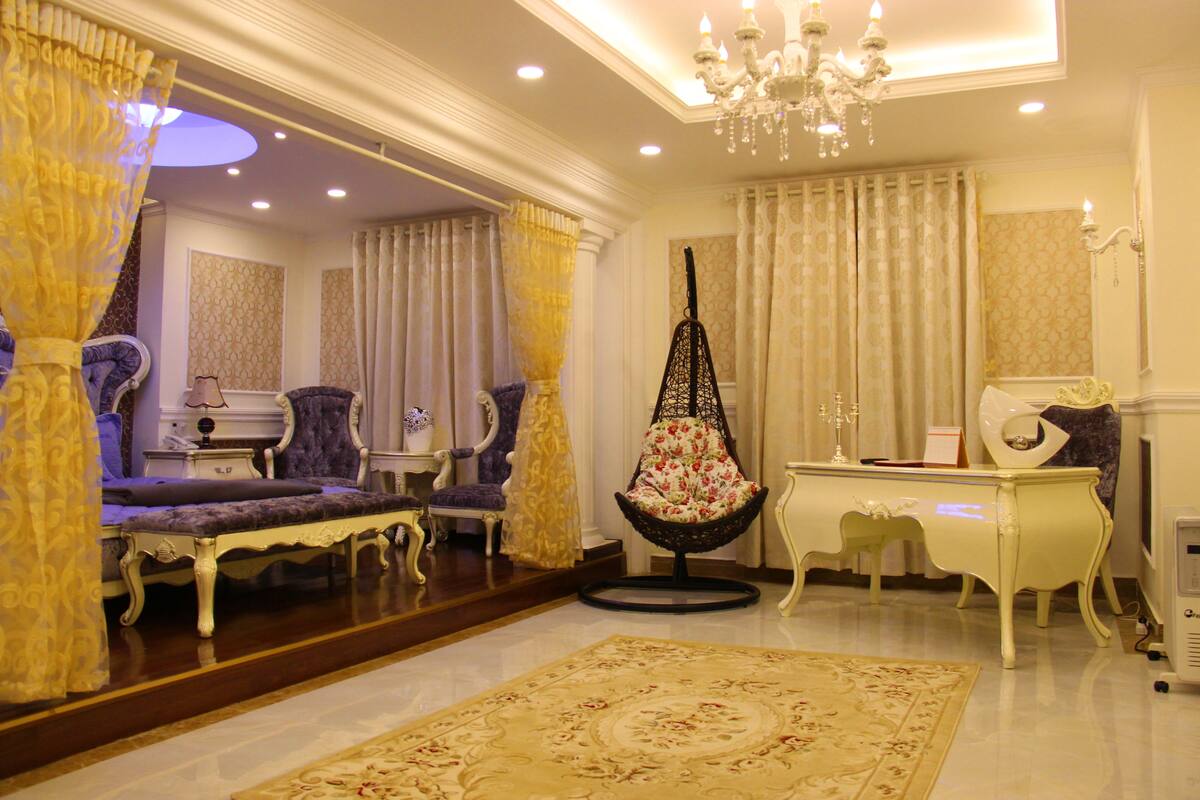 A luxurious living room with ornate furniture, a chandelier, and a large rug.